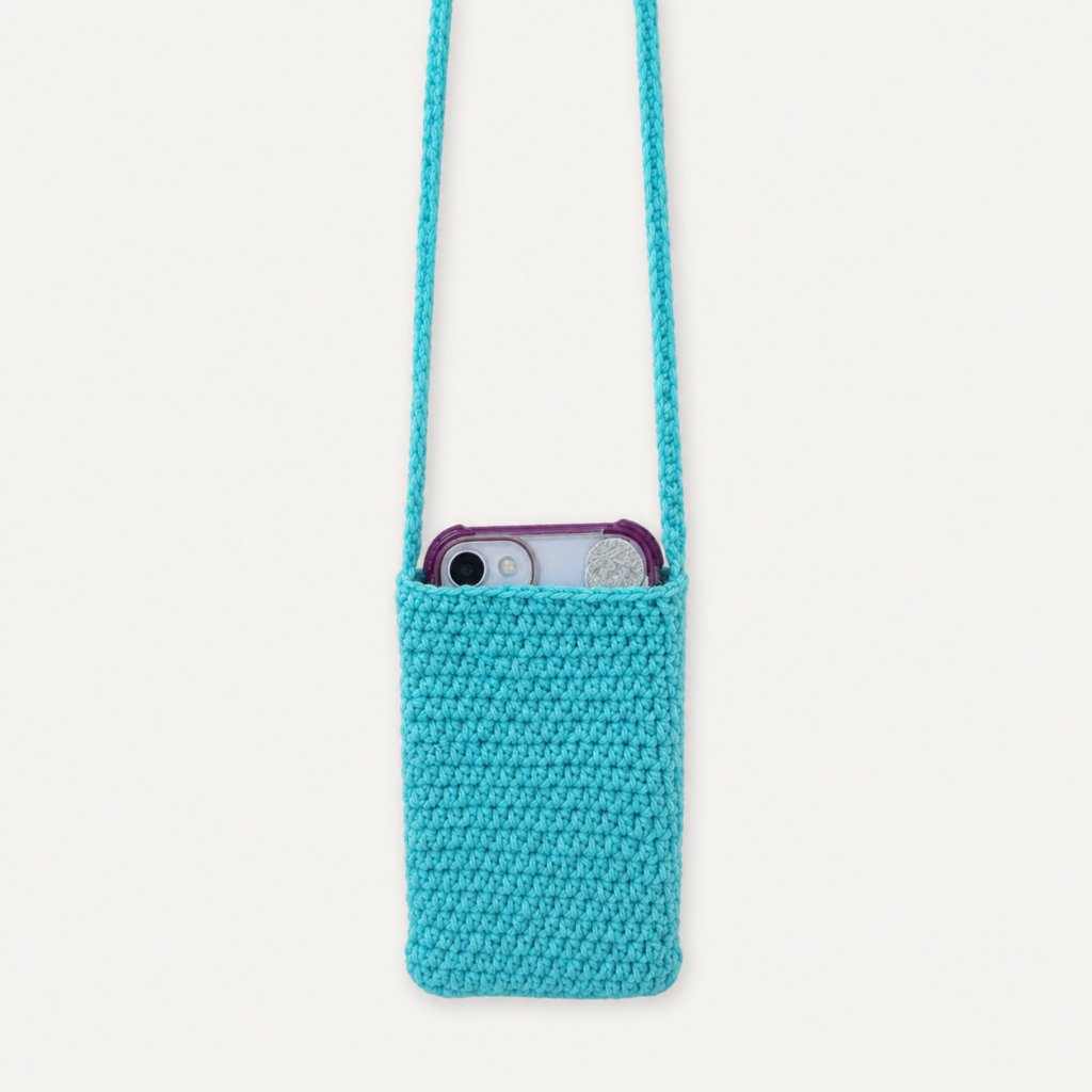 Handmade Jamaican aqua crochet shoulder phone pouch shown with a phone inside for size reference
