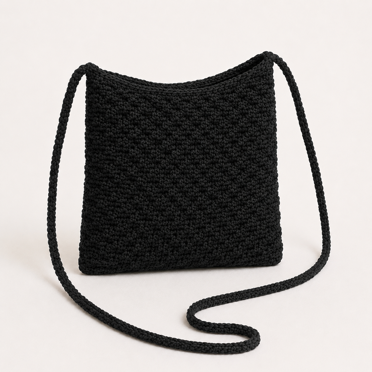 Handmade Jamaican black crochet crossbody phone pouch with matching strap arranged beside the pouch