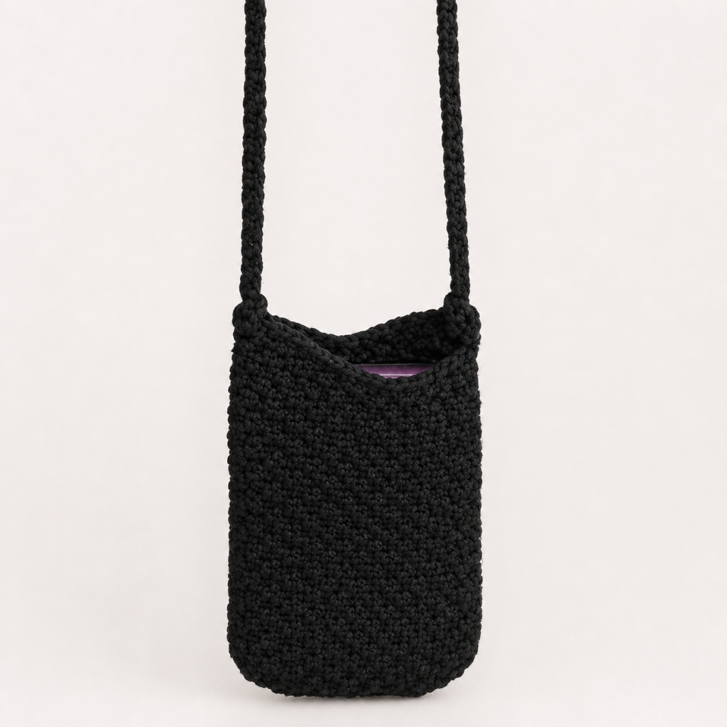 Handmade Jamaican black crochet crossbody phone pouch on a light neutral background
