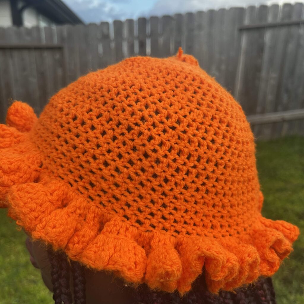 Handmade Jamaican bright orange crochet hat with open crown stitchwork and full ruffle brim