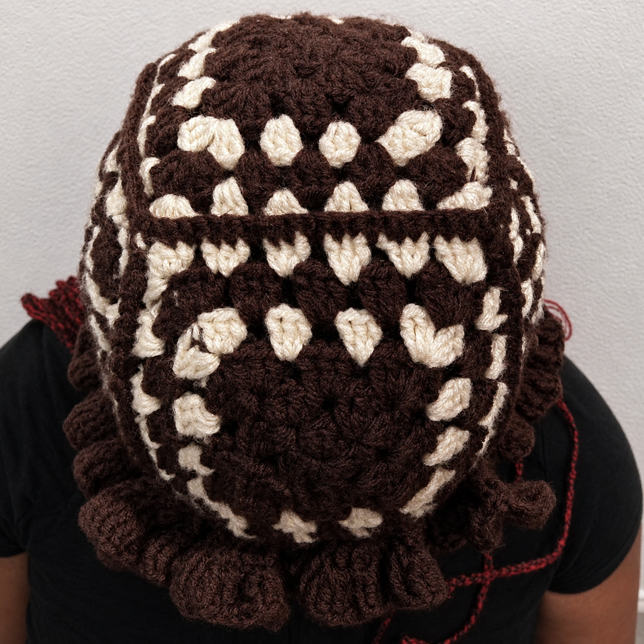 Close view of handmade Jamaican brown and cream granny-square crochet hat with chocolate-brown ruffle brim