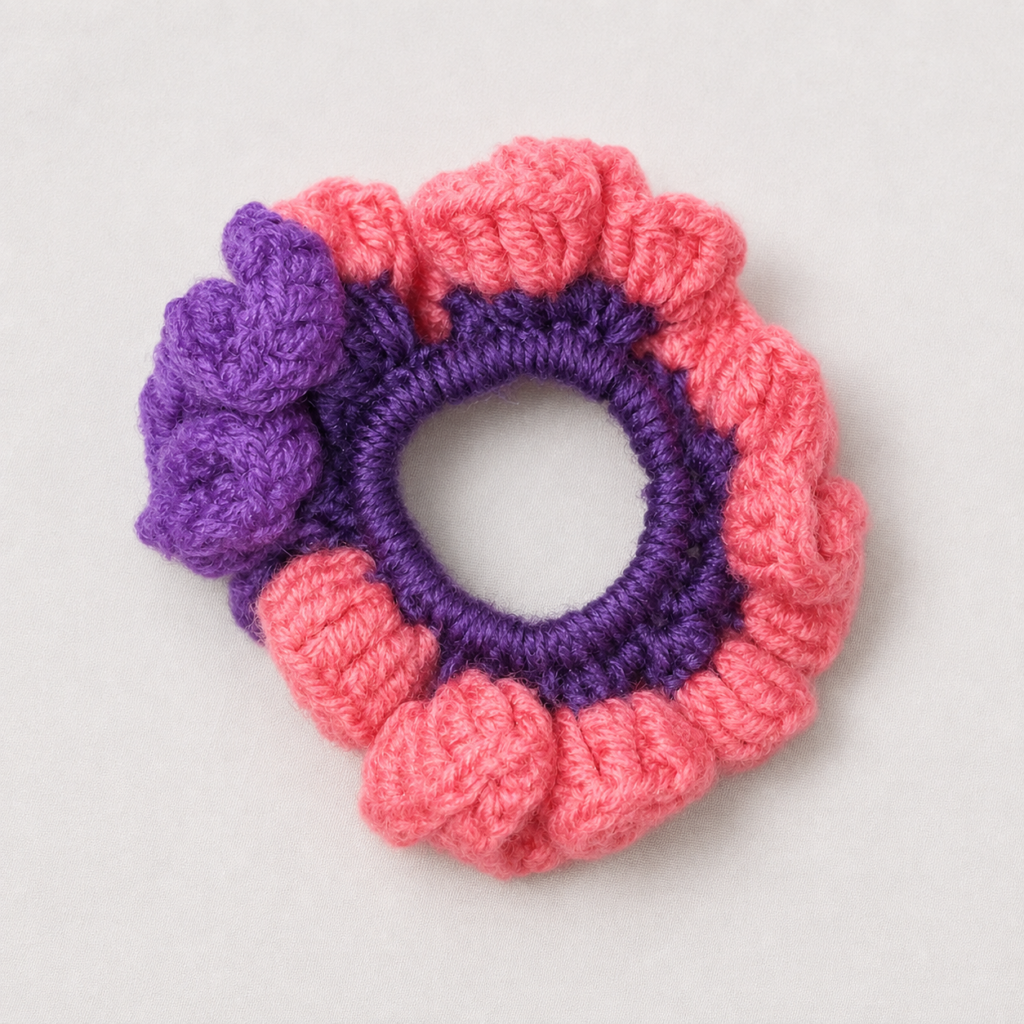 Handmade Jamaican coral-pink and deep-purple colorblock crochet scrunchie on a clean light background