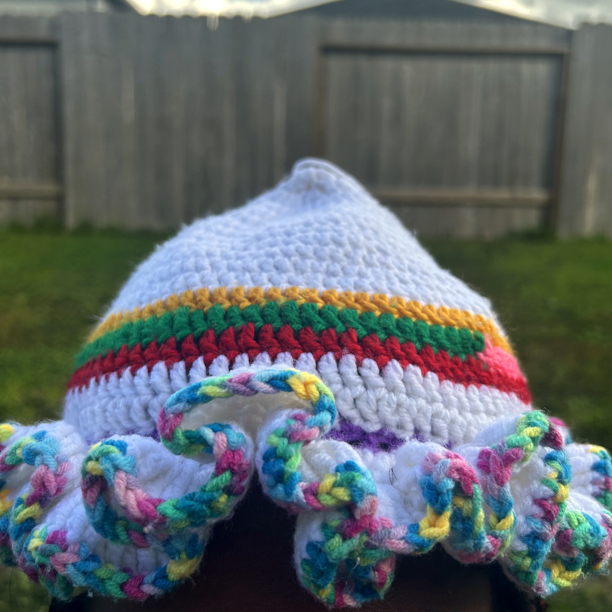 Front view of handmade Jamaican cream crochet hat with colorful striped band and variegated ruffle brim