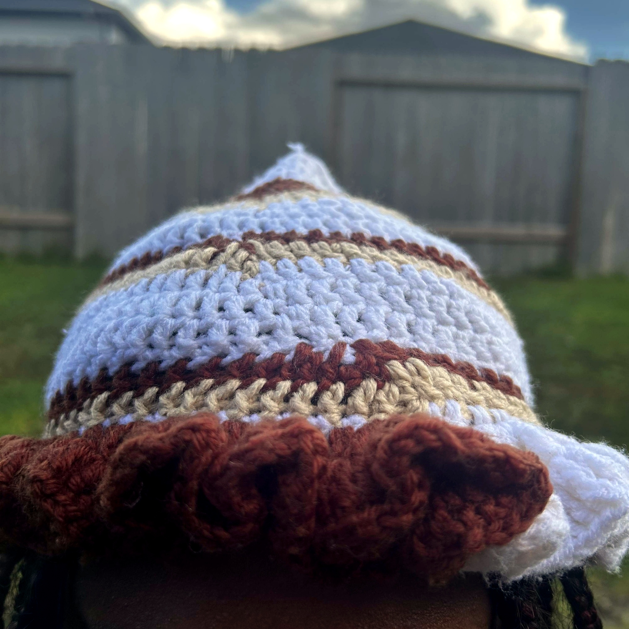 Close detail of rust-brown and cream crochet ruffles on handmade Jamaican striped hat