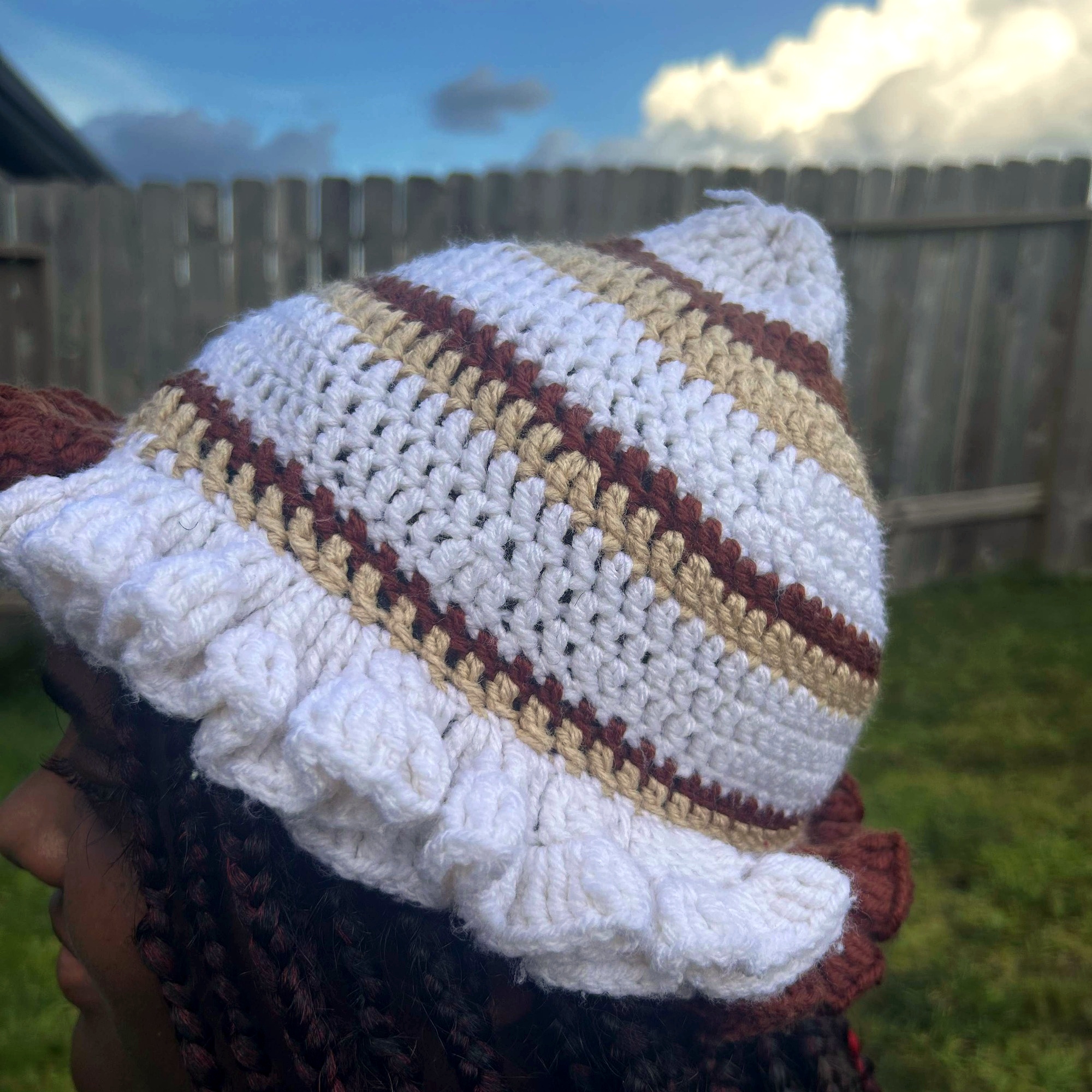 Angled view of handmade Jamaican cream tan and rust crochet hat with sculptural ruffle brim