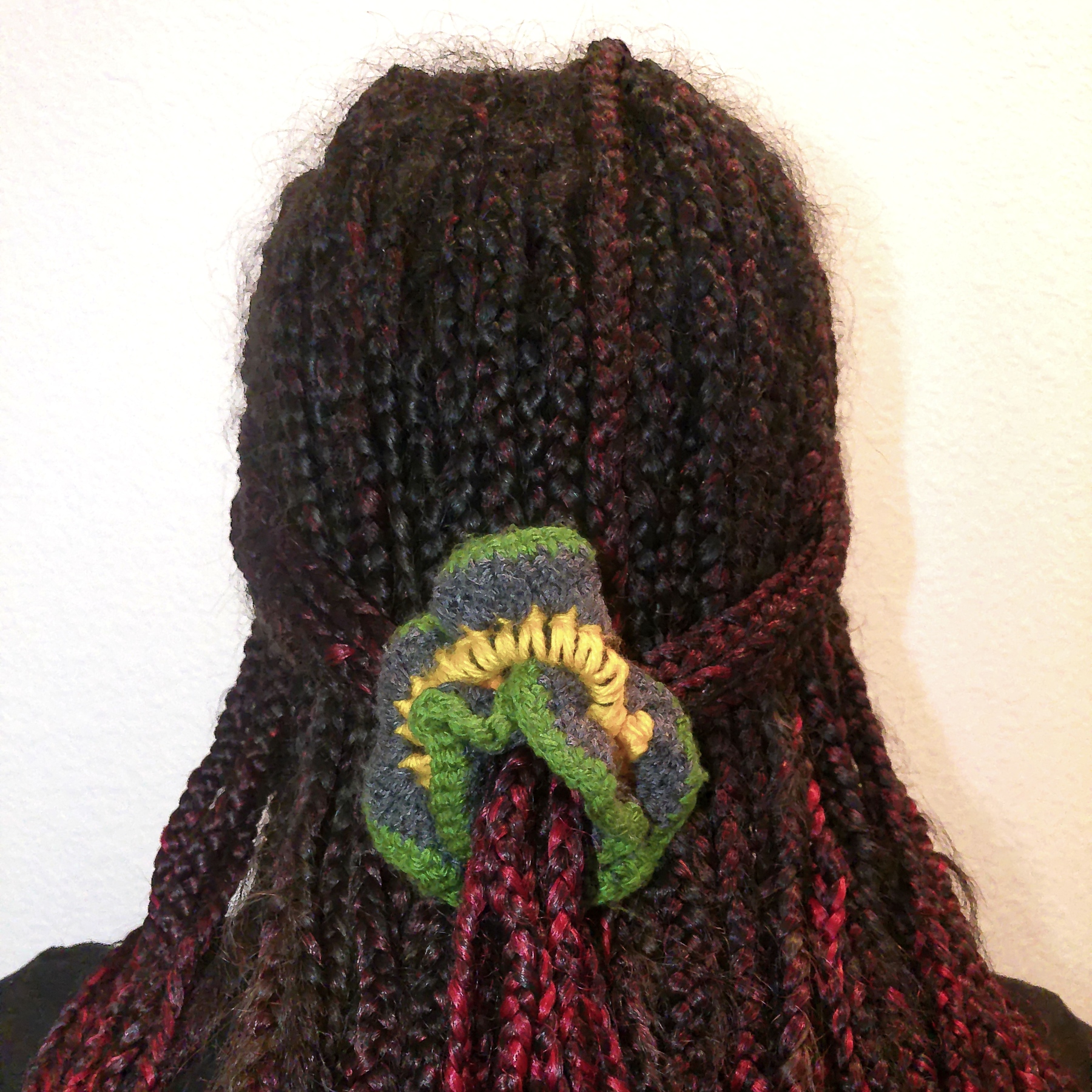 Handmade Jamaican green, charcoal-gray and golden-yellow crochet scrunchie shown worn in hair