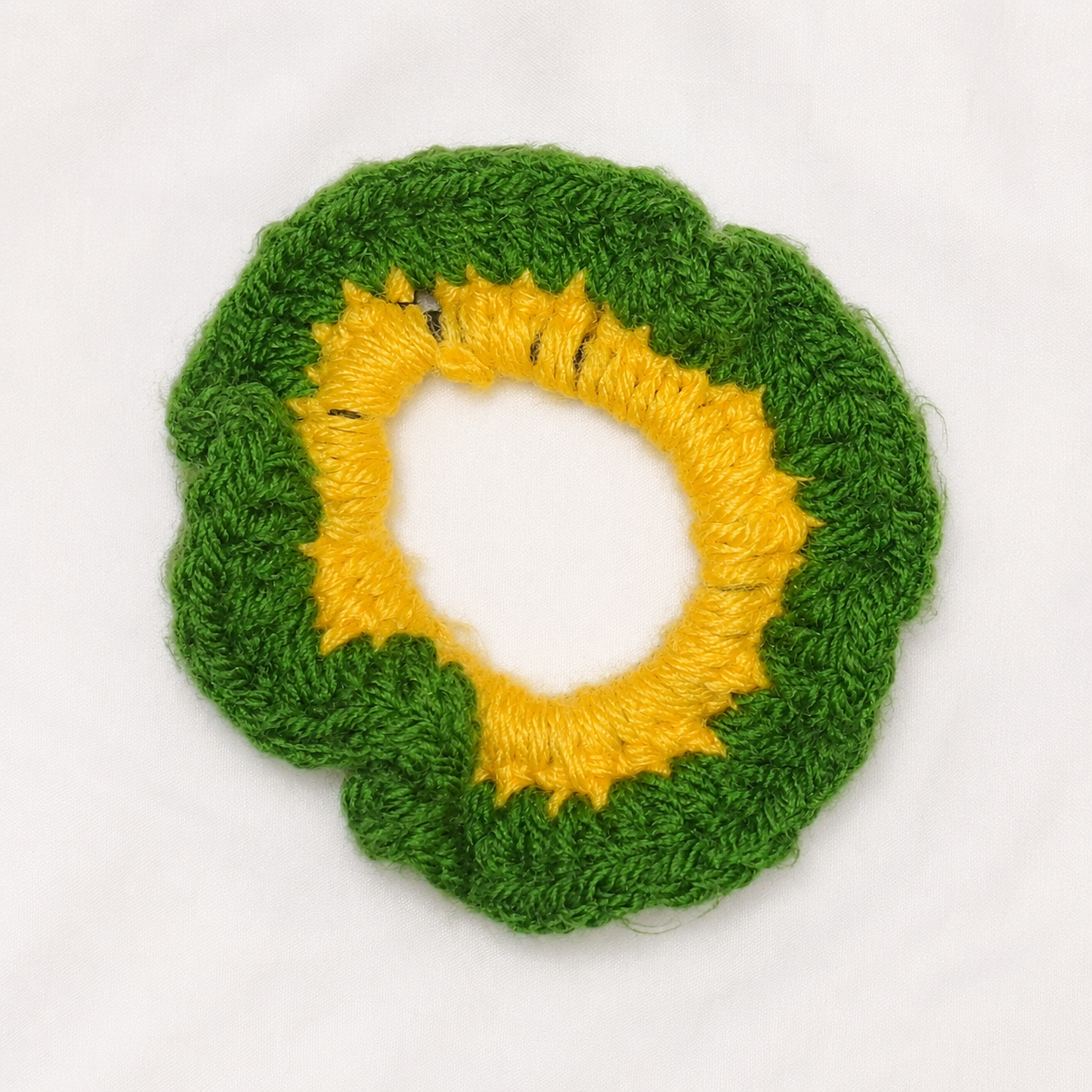 Handmade Jamaican green crochet scrunchie with yellow center on a clean white background