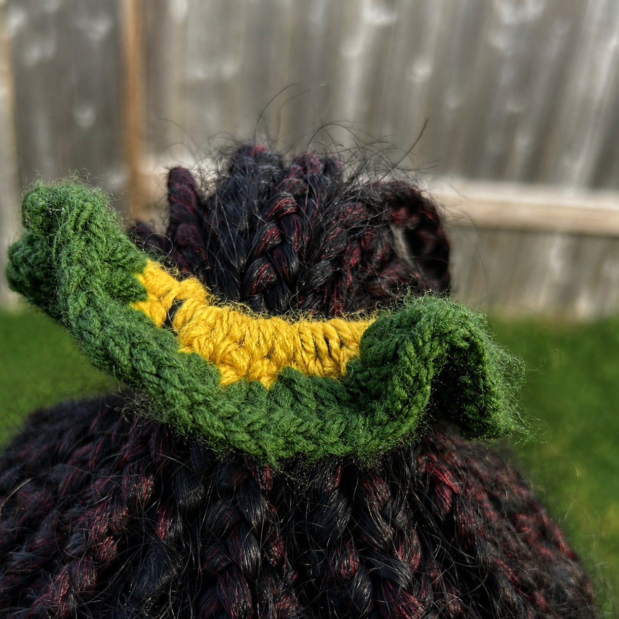Handmade Jamaican green crochet scrunchie with yellow center shown worn in braided hair