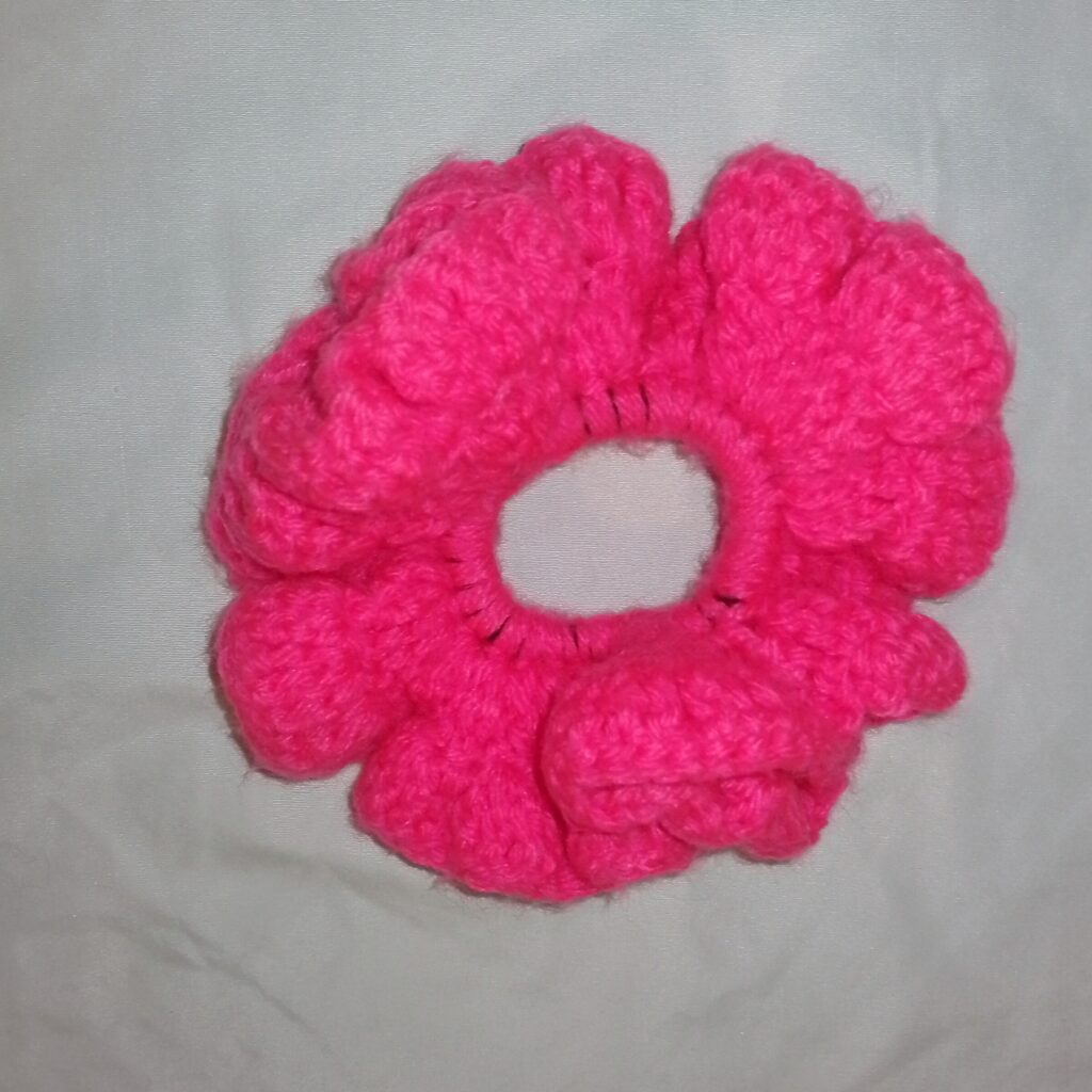 Handmade Jamaican hot-pink crochet scrunchie on a clean light background