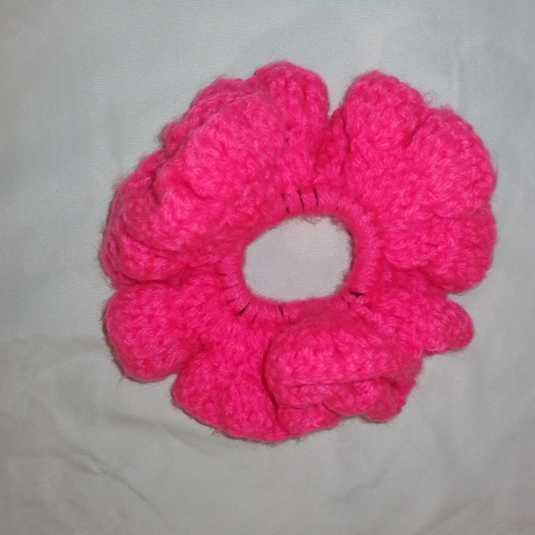 Handmade Jamaican hot-pink crochet scrunchie on a clean light background