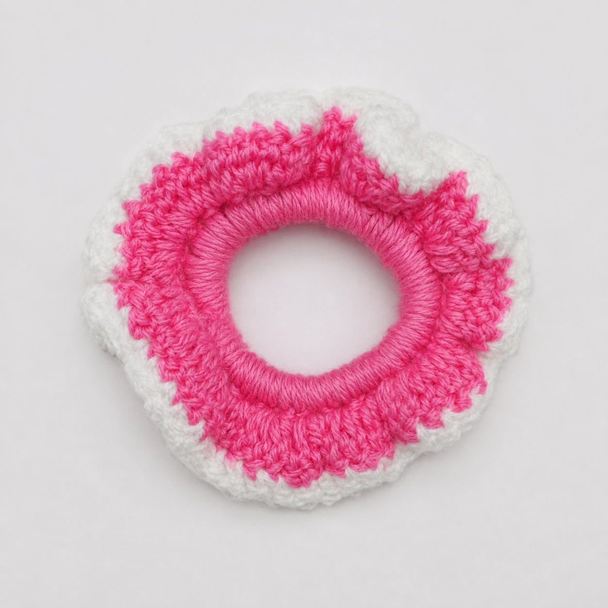 Handmade Jamaican hot-pink and white crochet scrunchie on a clean white background