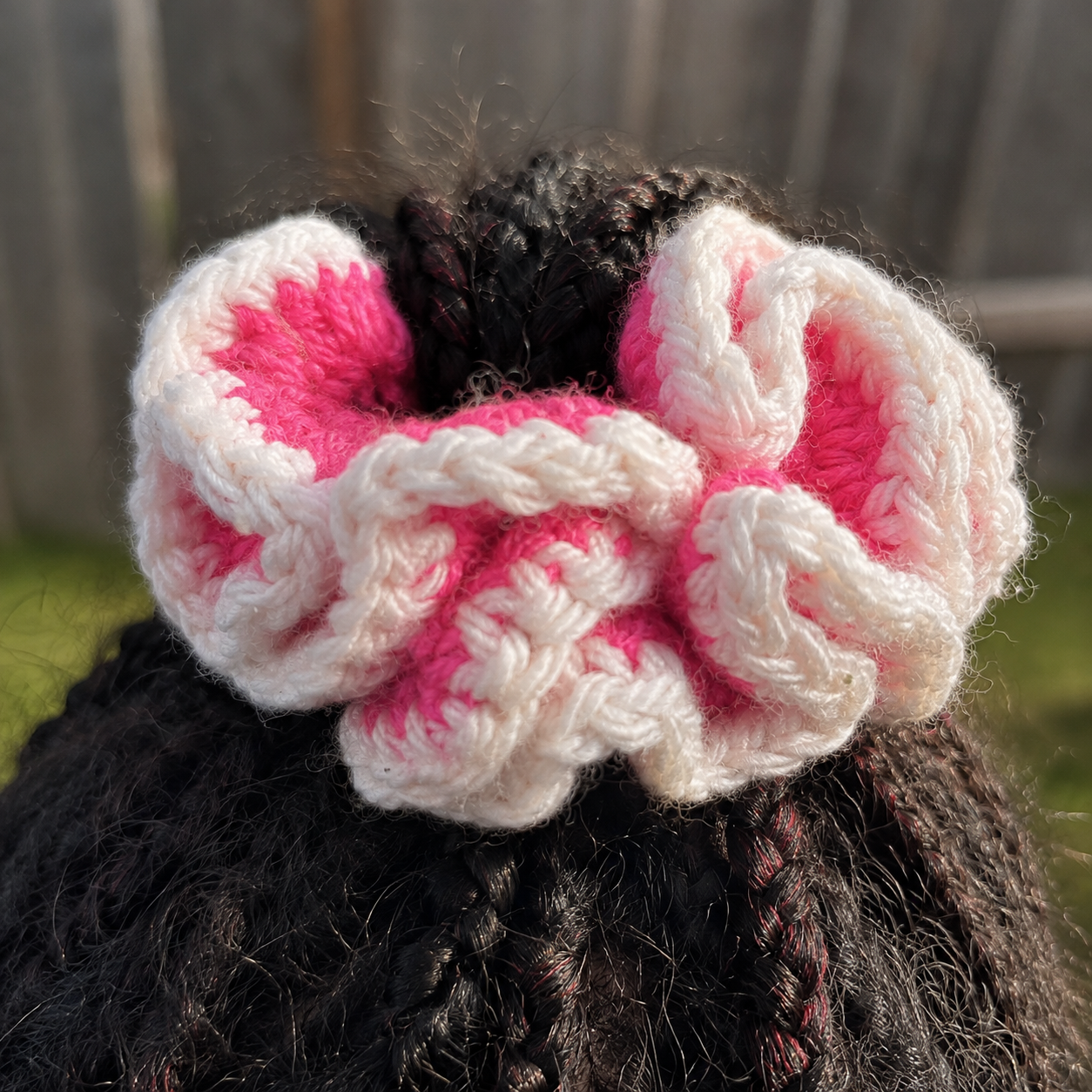 Handmade Jamaican hot-pink and white crochet scrunchie shown worn in hair