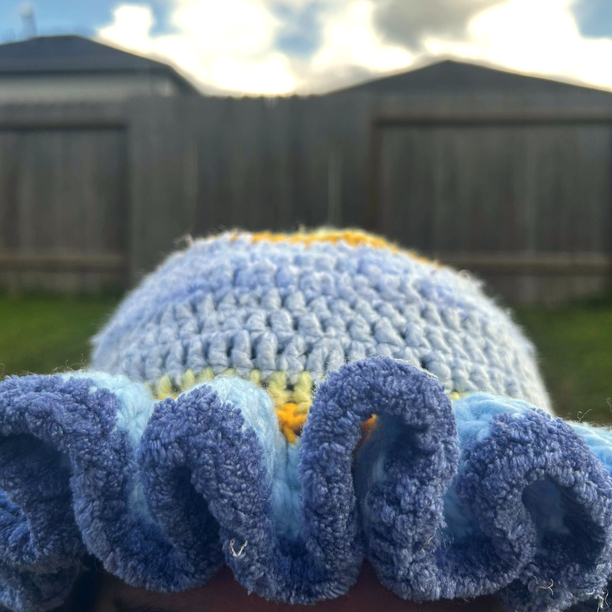Close detail of deep-blue edged crochet ruffles on handmade Jamaican light blue and gold hat
