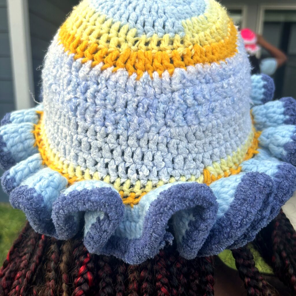 Rear view of handmade Jamaican light blue and gold crochet hat with full deep-blue ruffled brim