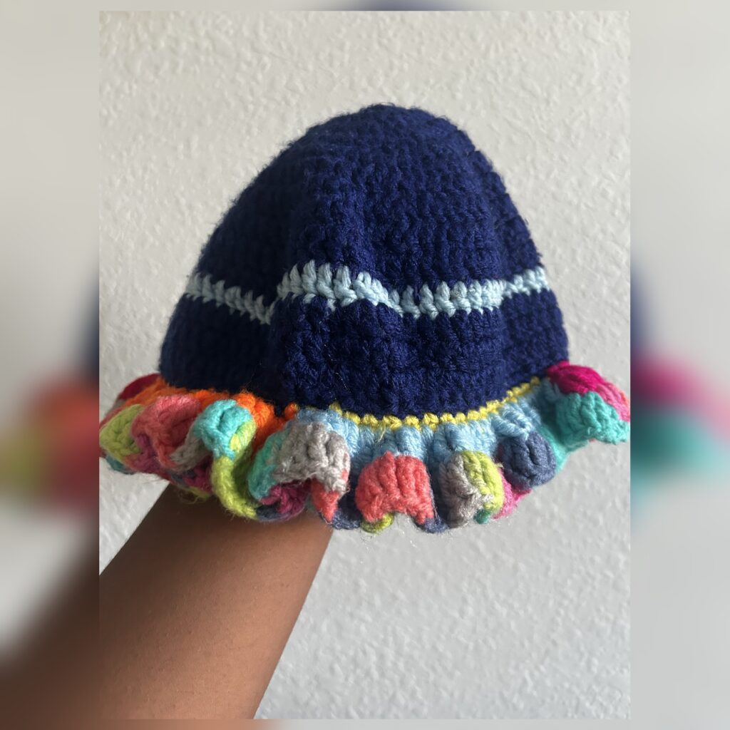 Handmade Jamaican navy blue crochet hat with light blue stripe and multicolor curled ruffle brim