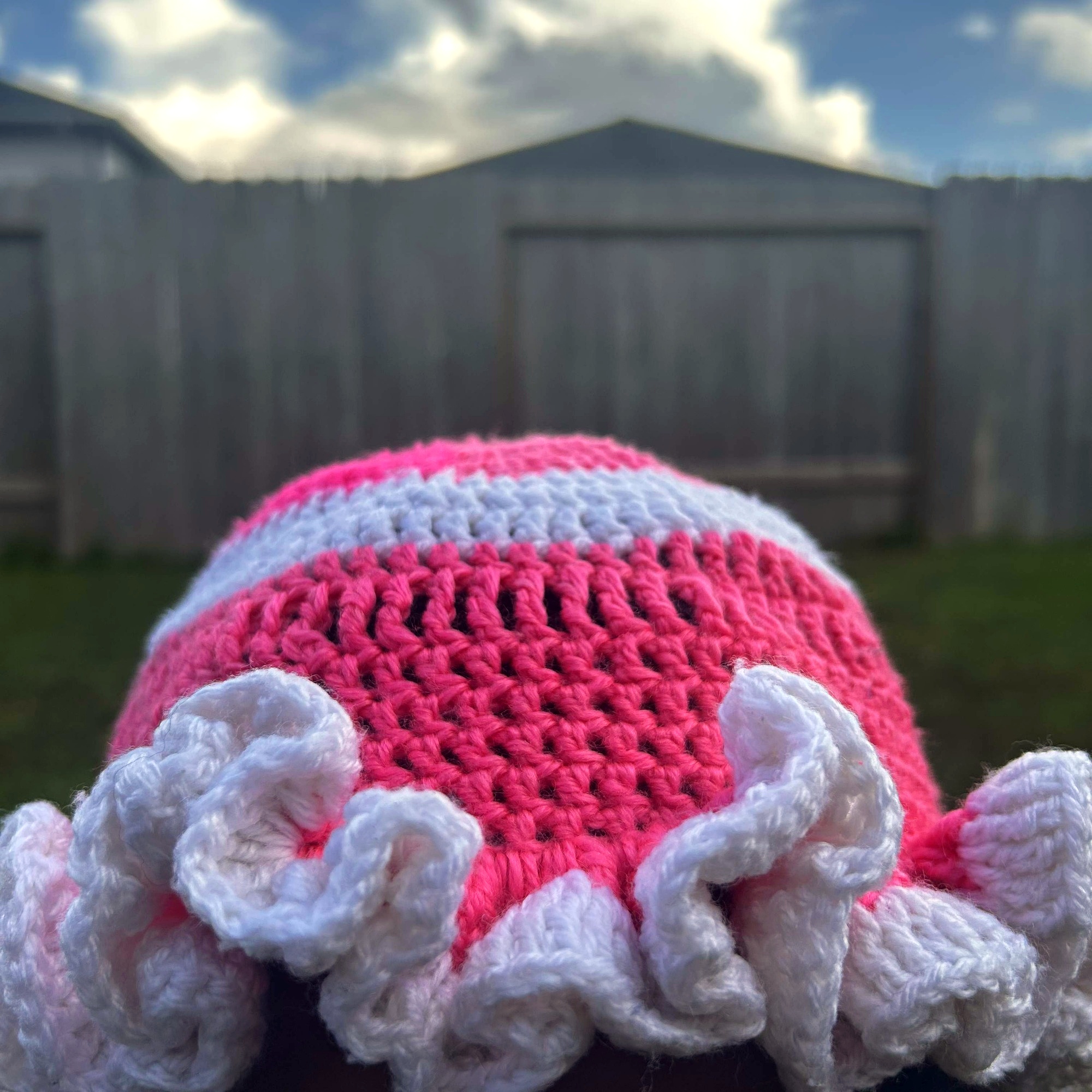 Front view of handmade Jamaican pink and white crochet hat with oversized white ruffled brim