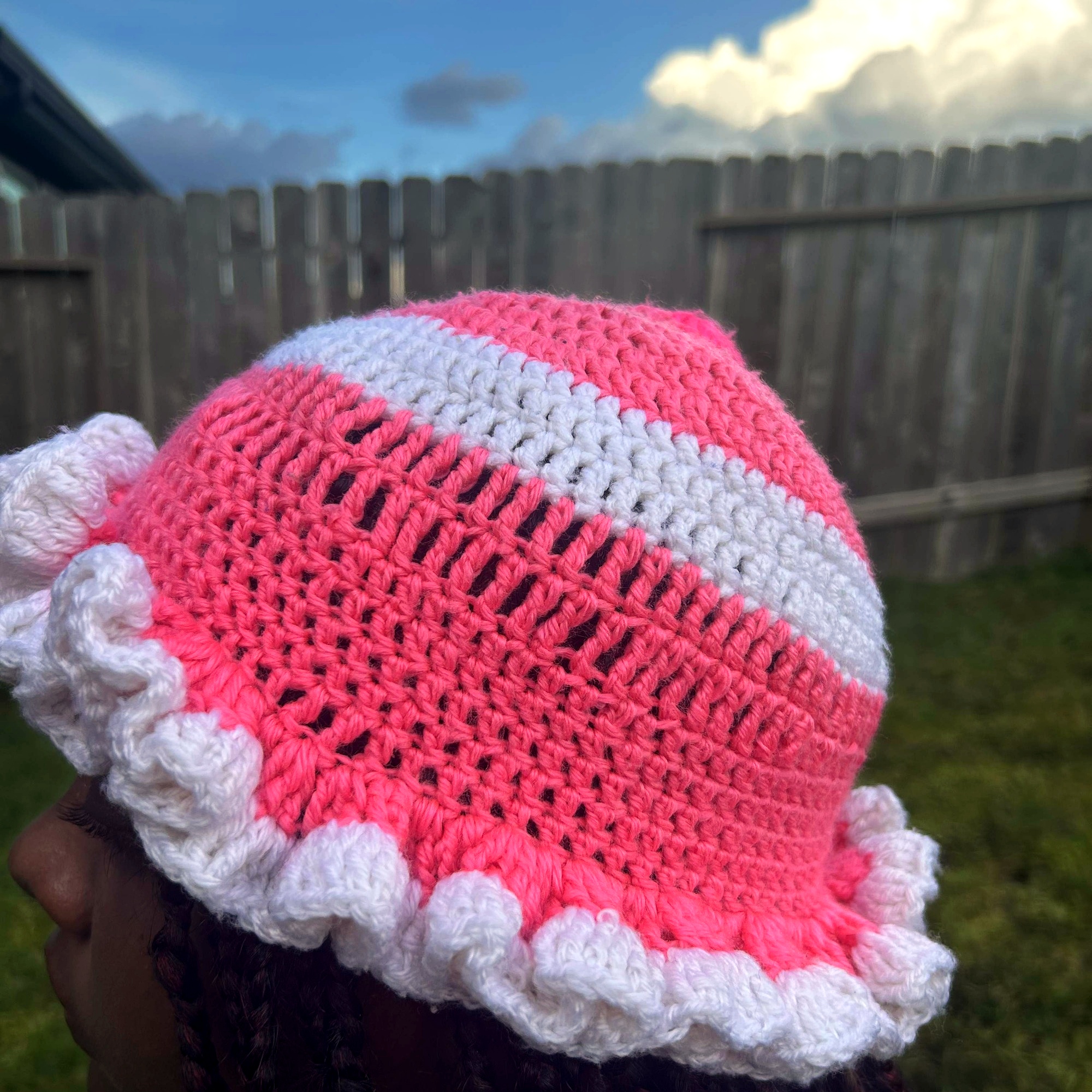Side profile of handmade Jamaican pink and white crochet hat with layered white ruffle brim