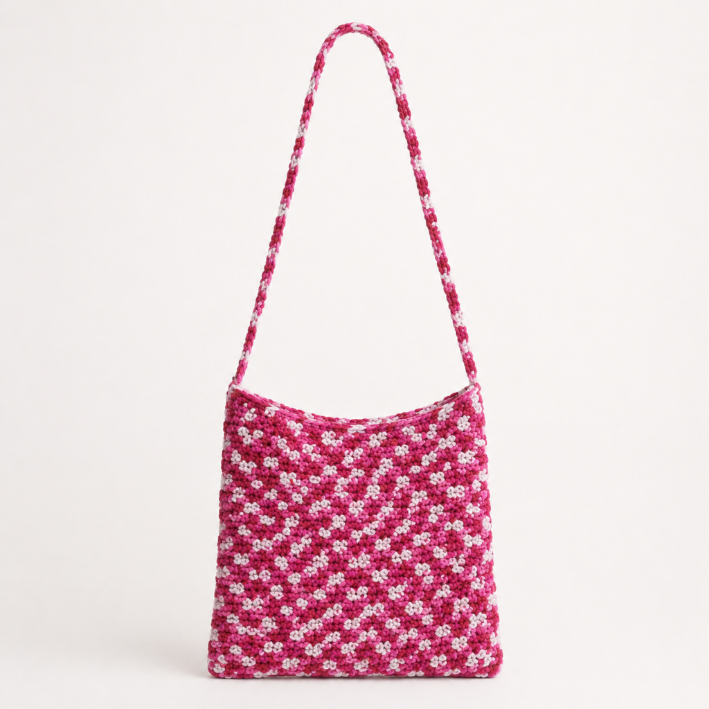 Handmade Jamaican pink and white variegated crochet shoulder bag on a light neutral background