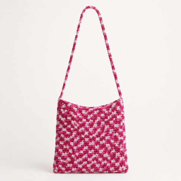 Handmade Jamaican pink and white variegated crochet shoulder bag on a light neutral background