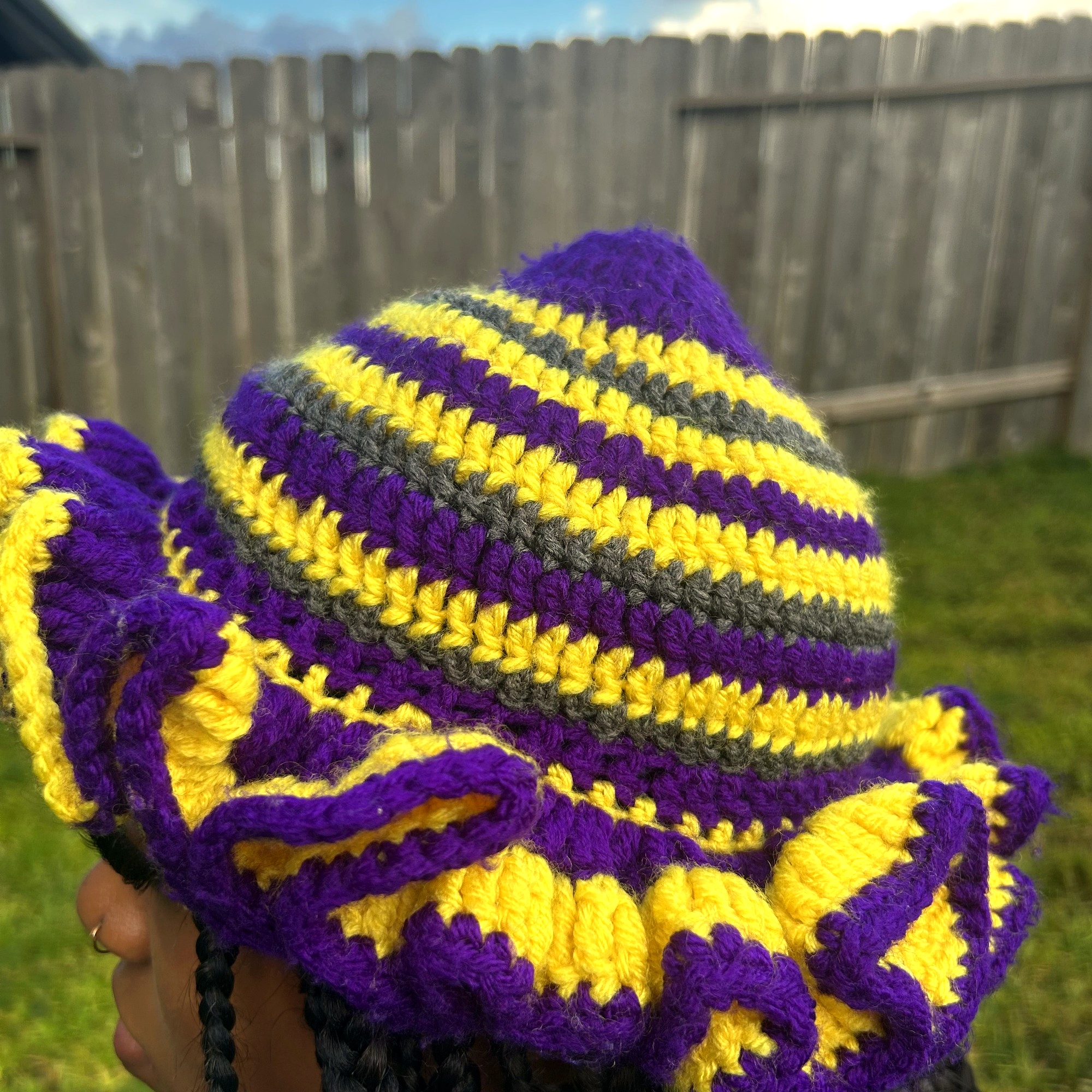 Angled view of handmade Jamaican purple gold and charcoal ruffle-brim crochet hat
