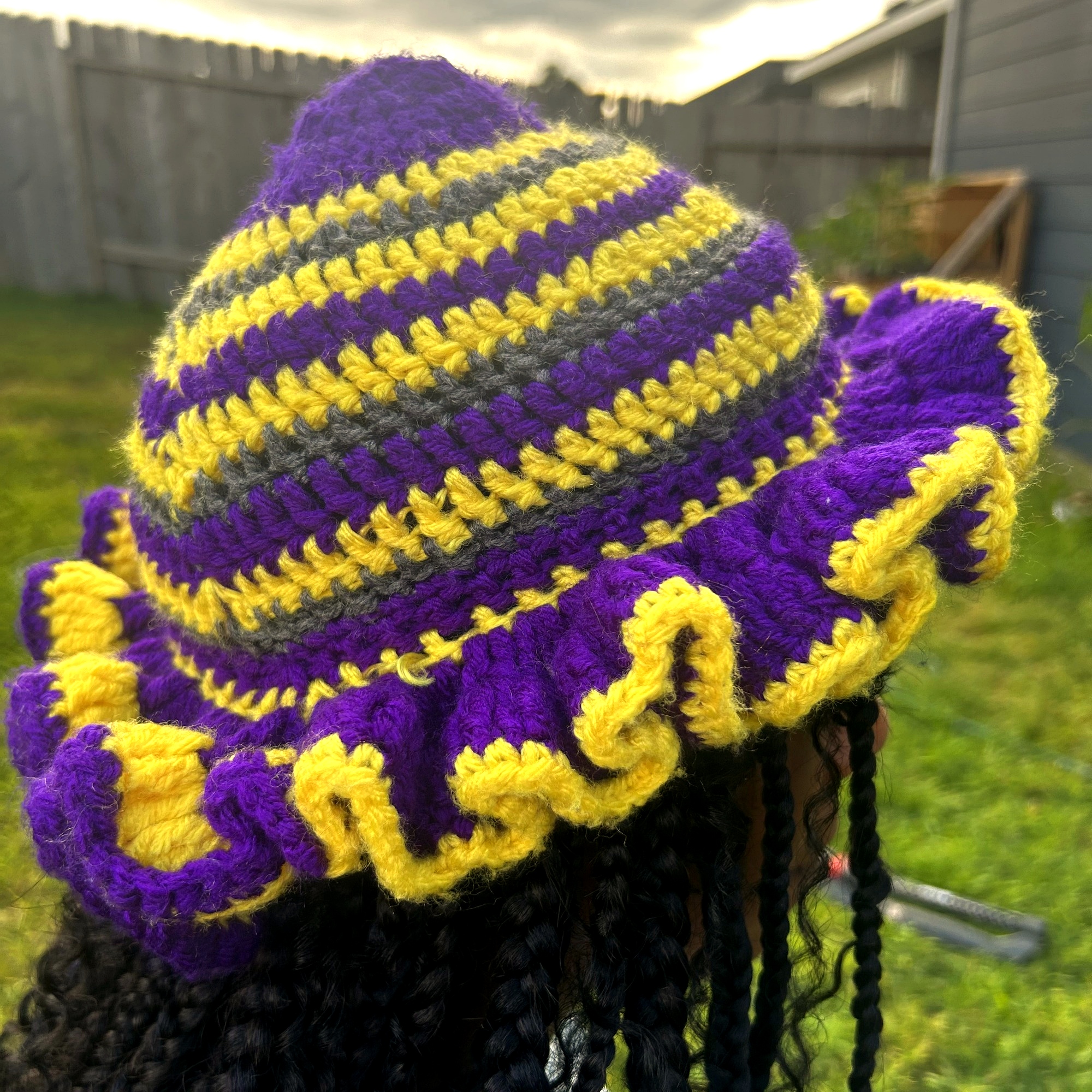 Side profile of handmade Jamaican purple gold and charcoal crochet hat with ruffled brim