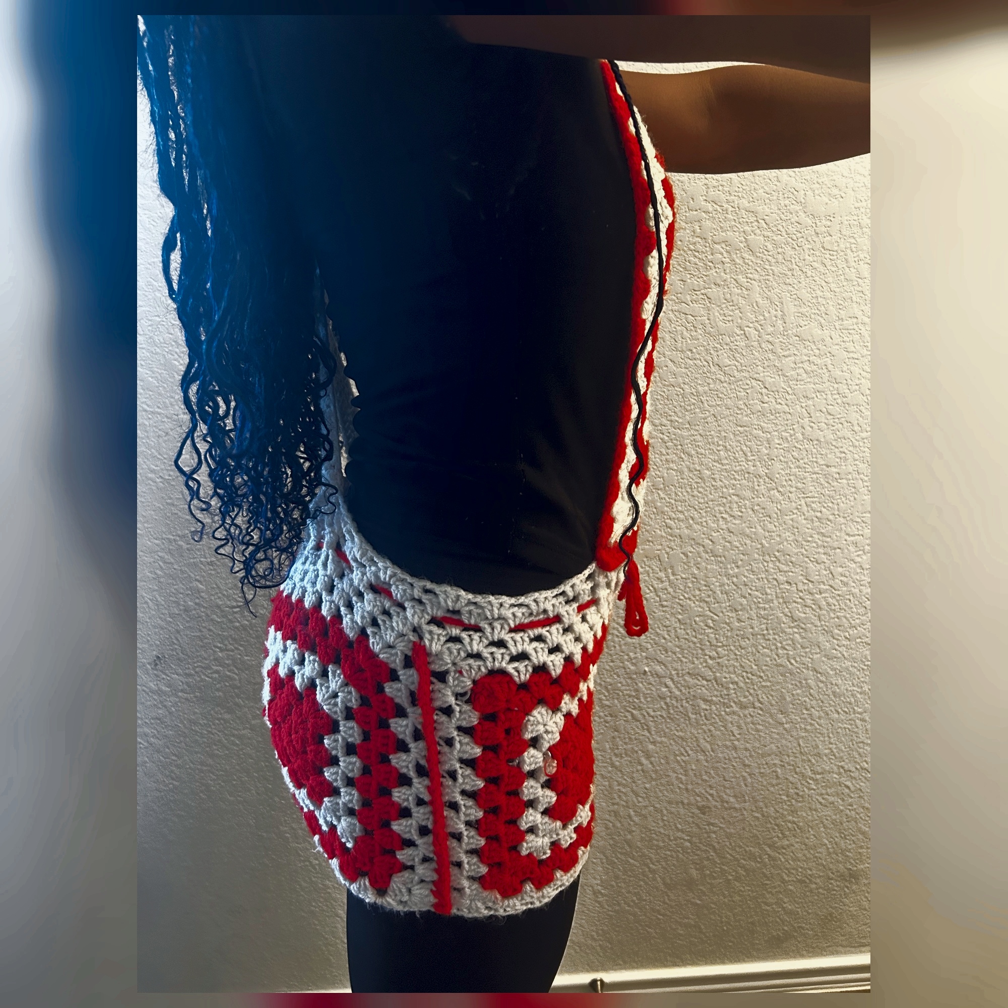 Side view of handmade Jamaican red and cream granny-square crochet skirt romper with open side and drawstring waist