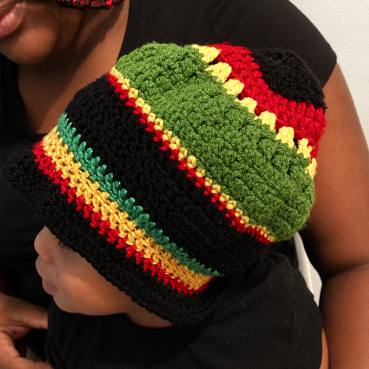 Angled worn view of handmade Jamaican red gold green and black crochet bucket hat