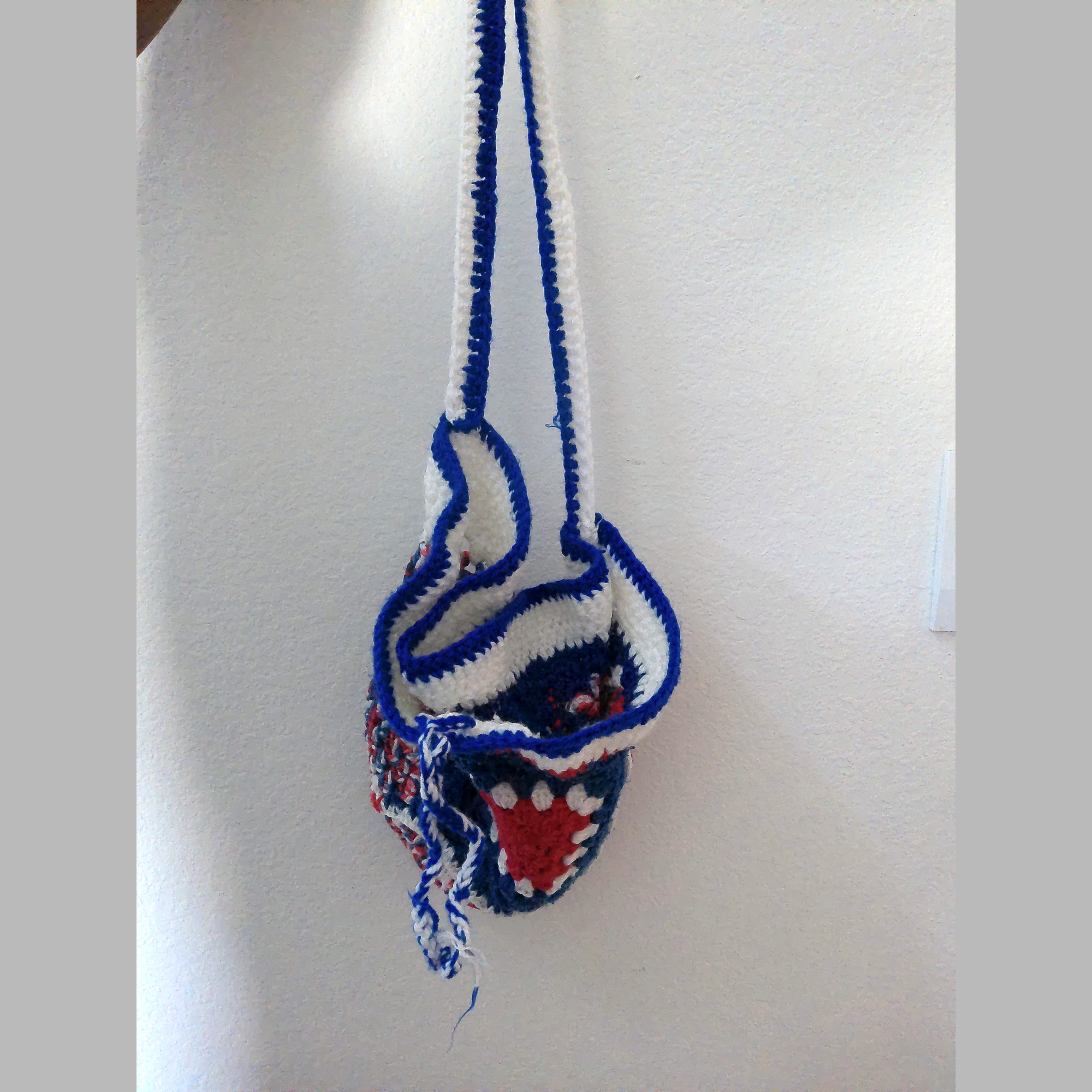 Angled view of handmade Jamaican red white and blue crochet shoulder bag