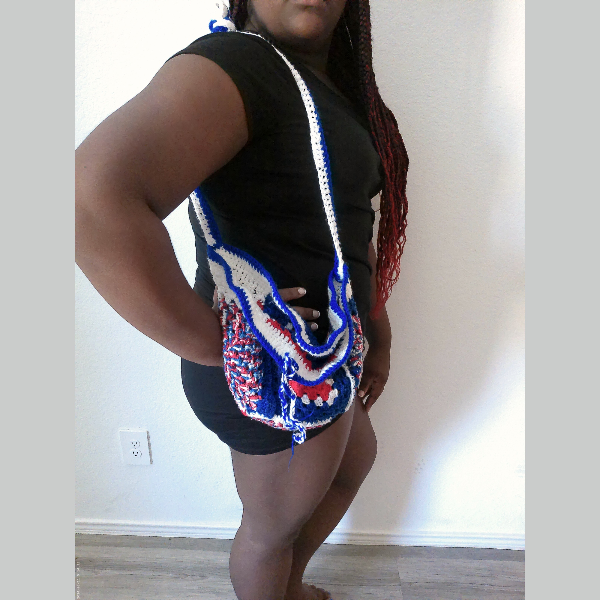 Handmade Jamaican red white and blue crochet shoulder bag shown worn on the shoulder