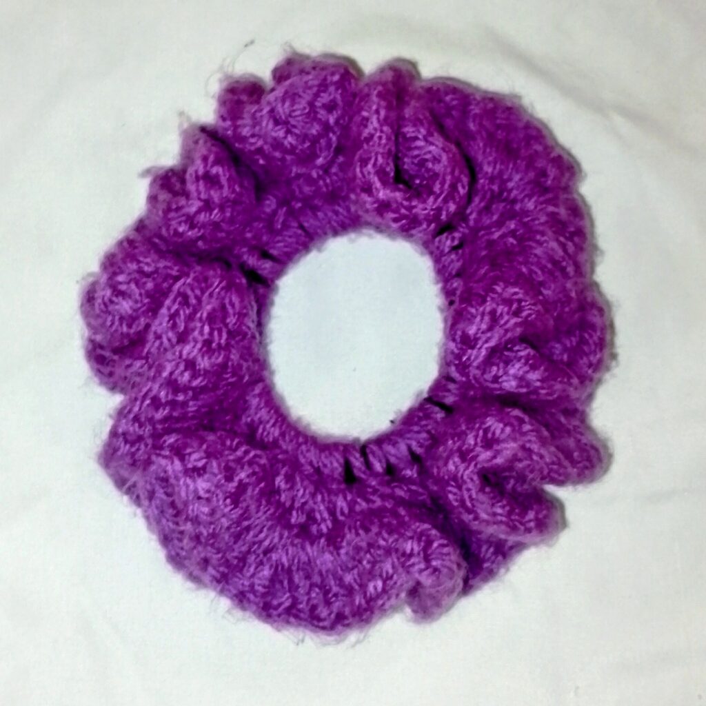 Handmade Jamaican solid-purple crochet scrunchie on a clean light background