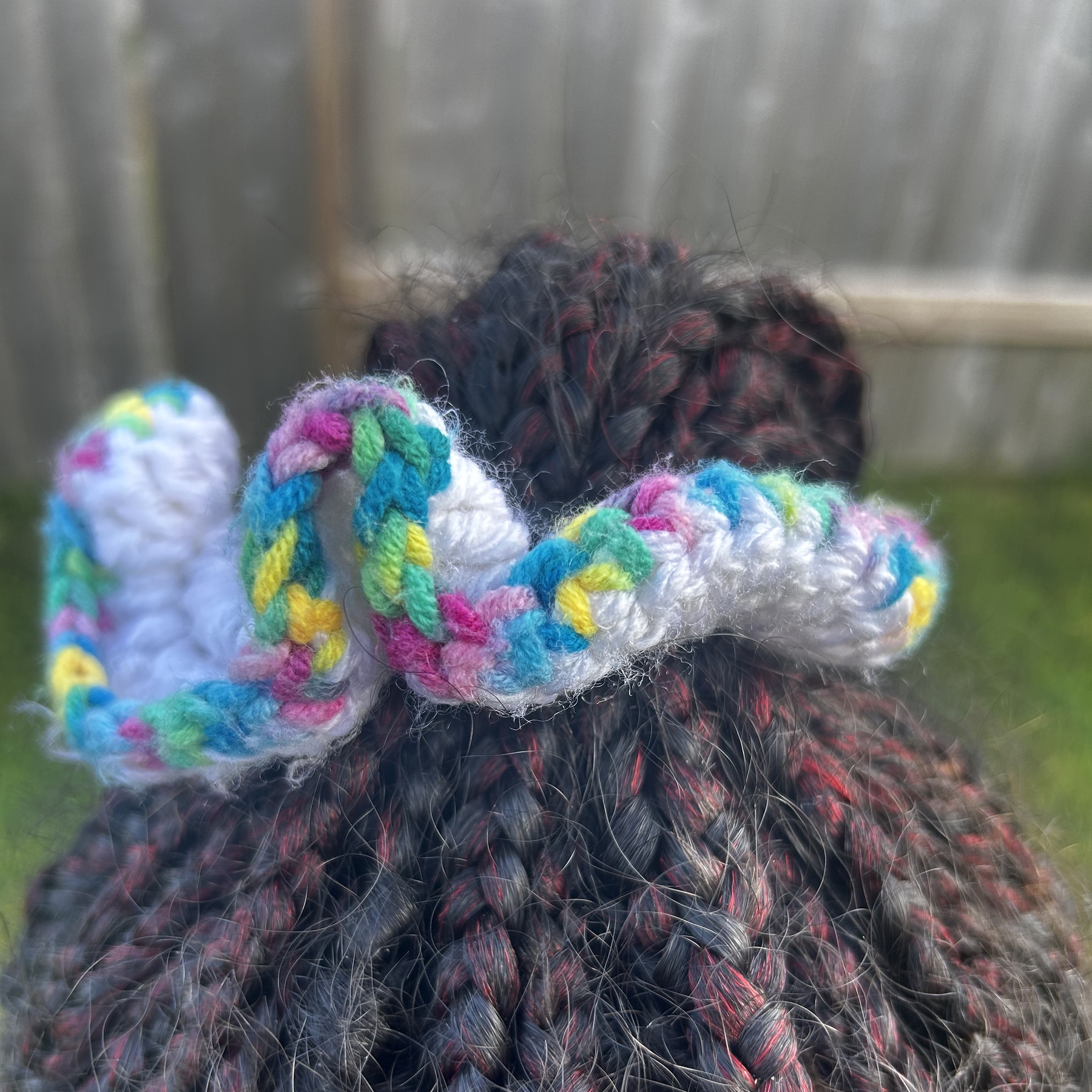 Handmade Jamaican white crochet scrunchie with pastel multicolor trim shown worn in hair