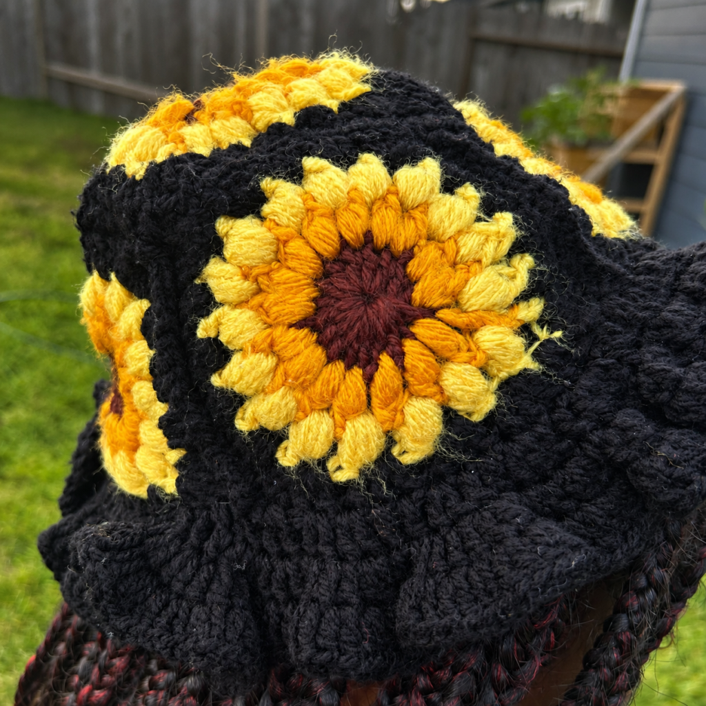 Close-up of black crochet hat with layered yellow and golden sunflower motifs