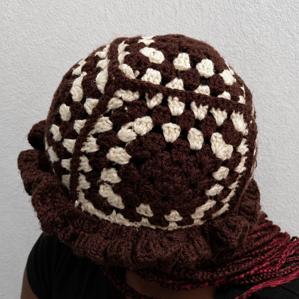 Close angled view of a handmade brown and cream Jamaican granny-square crochet ruffle-brim hat