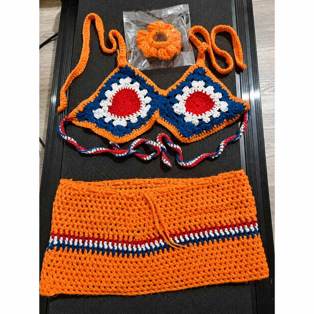 Orange handmade crochet halter top, mini skirt and matching scrunchie arranged as a complete set
